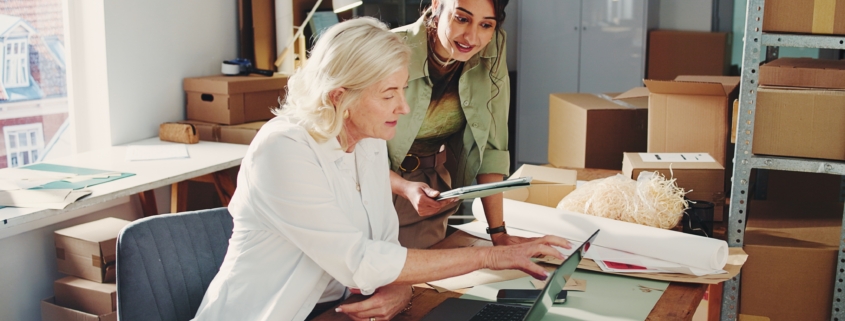 Two businesswomen in an office discussing business financing strategies and growth cycles.