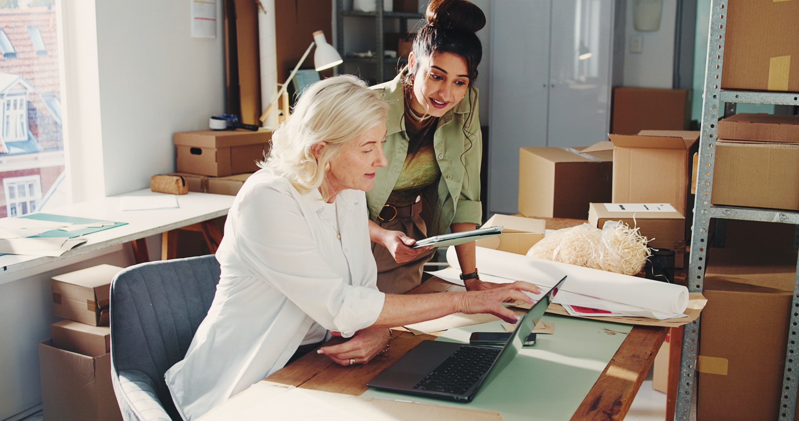 Two businesswomen in an office discussing business financing strategies and growth cycles.
