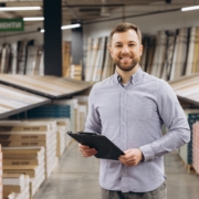 Smiling man holding a clipboard planning how to slow small business growth without losing momentum.