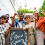 Diverse,Group,Of,People,In,Aprons,Celebrating,A,Grand,Opening. A diverse group of workers with aprons on elaborate the opening of a new business.