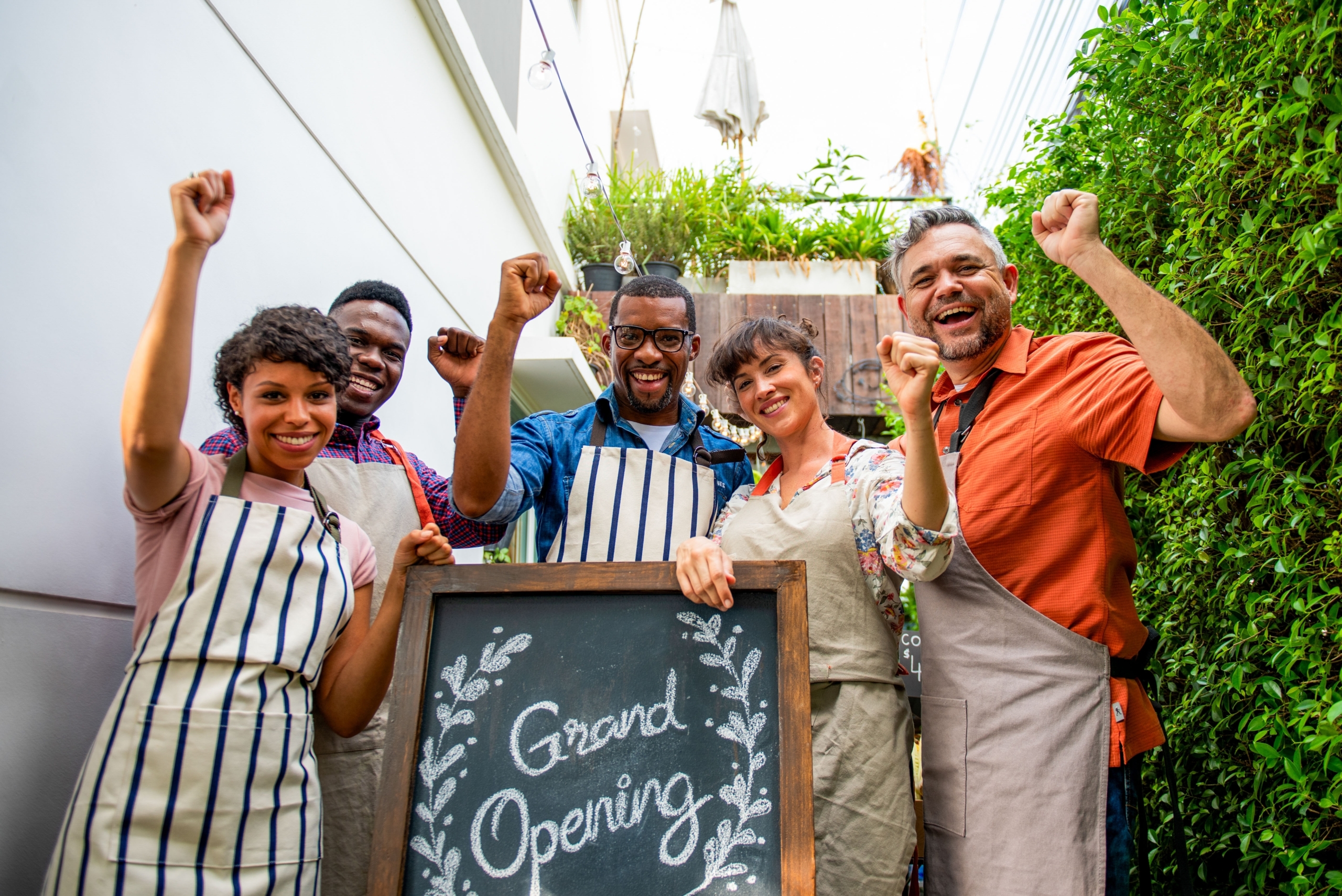 A diverse group of workers with aprons on elaborate the opening of a new business.