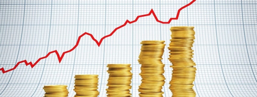 Stacks of golden coins coins with a red financial graph behind.