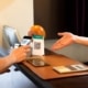 Close up man hand scanning QR code with cell phone, woman hand pointing to QR code.