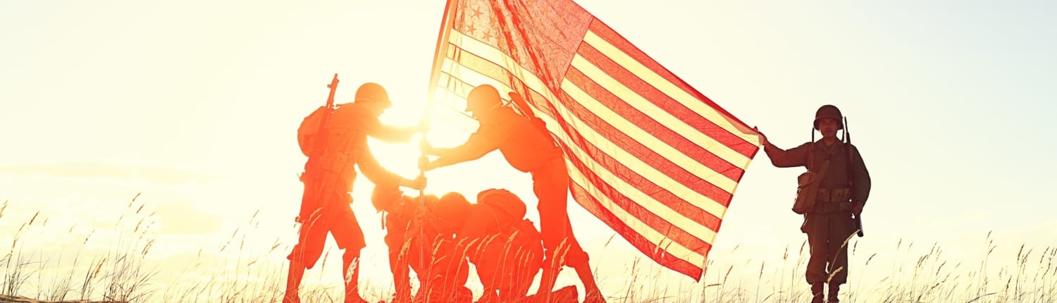 Soldiers raise American flag before a golden sunset